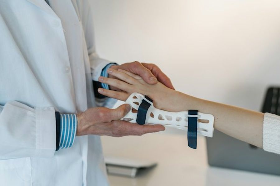 Terapeut care ajustează o orteză pe încheietura unui pacient